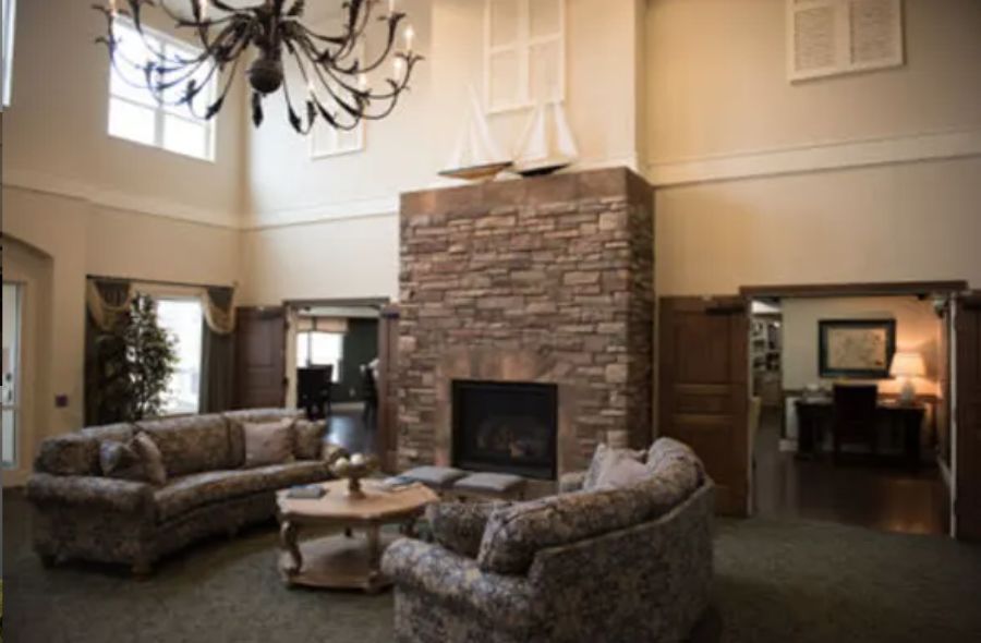 A cozy living room with a stone fireplace, elegant chandelier, and comfortable sofas.