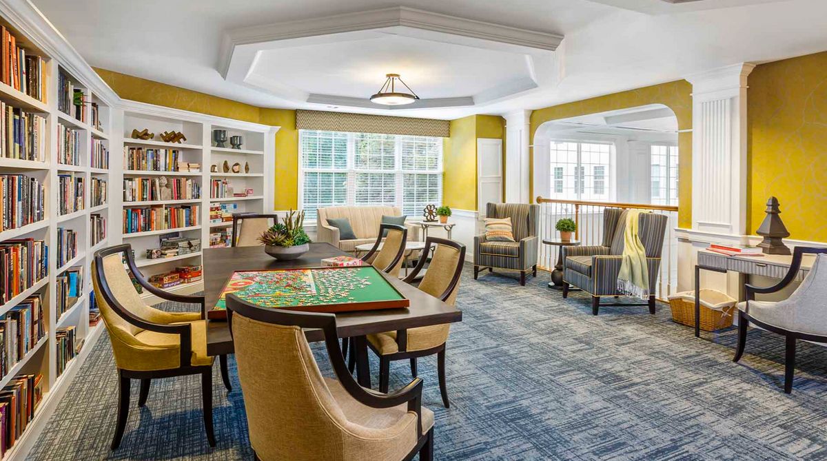 A cozy living space with a table, chairs, bookshelves, and ample natural light.