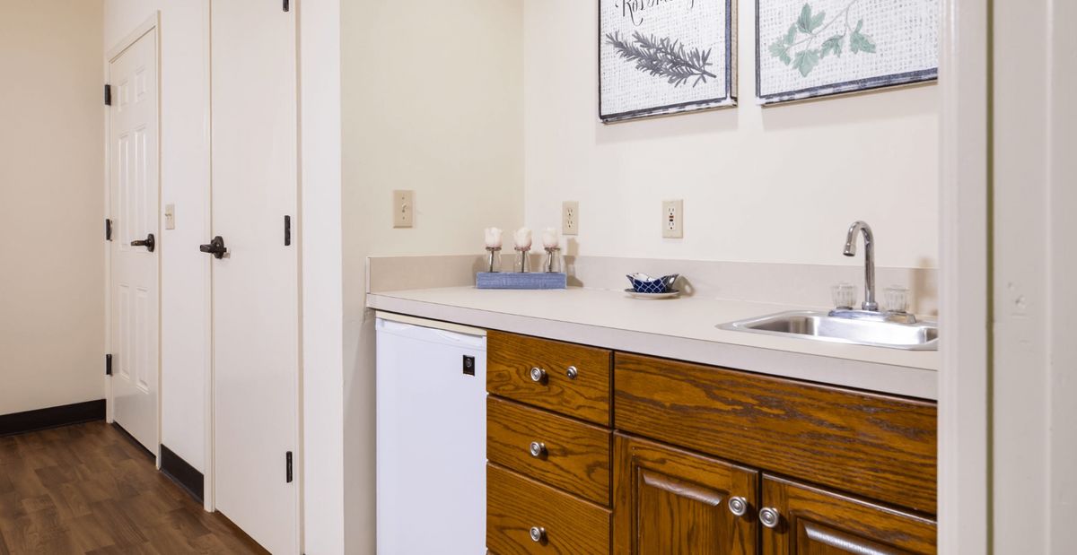 A compact kitchen area with wooden cabinets, a small refrigerator, and a sink.
