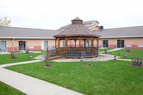 A charming wooden gazebo situated in the middle of a grassy courtyard surrounded by buildings.