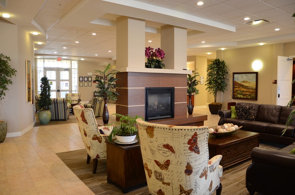 A modern lobby with comfortable seating and a central fireplace, adorned with plants and stylish decorations.