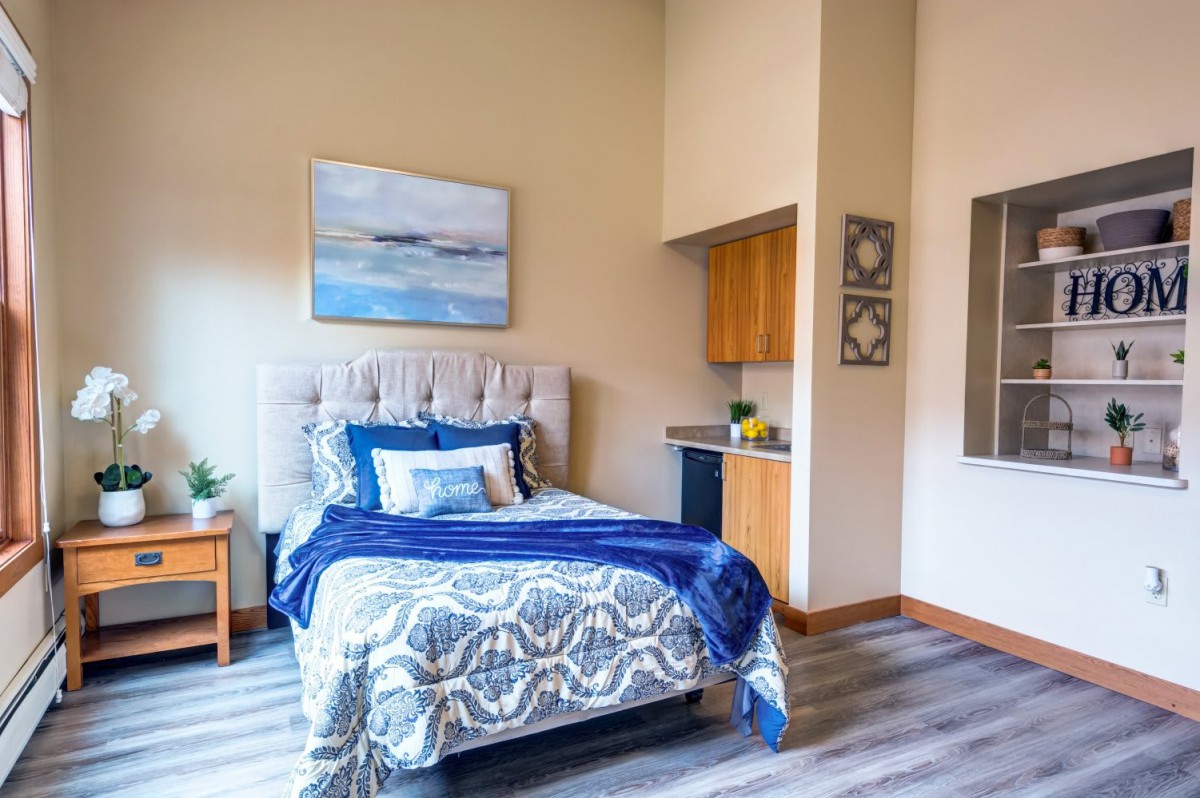 A modern bedroom with a plush bed featuring blue accents and stylish decor.