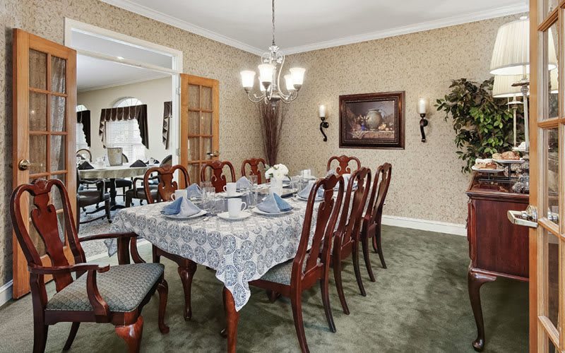 A formal dining room with a large table, elegant chairs, and a decorative chandelier.