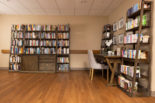 A welcoming reading nook featuring bookshelves filled with books and a comfortable table and chairs.