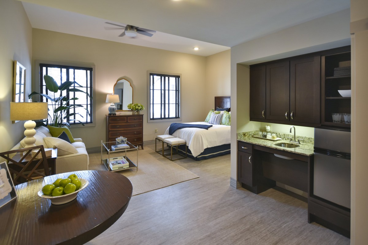 A modern and cozy bedroom with elegant interior design, featuring a comfortable bed, stylish furniture, and a small kitchenette area.