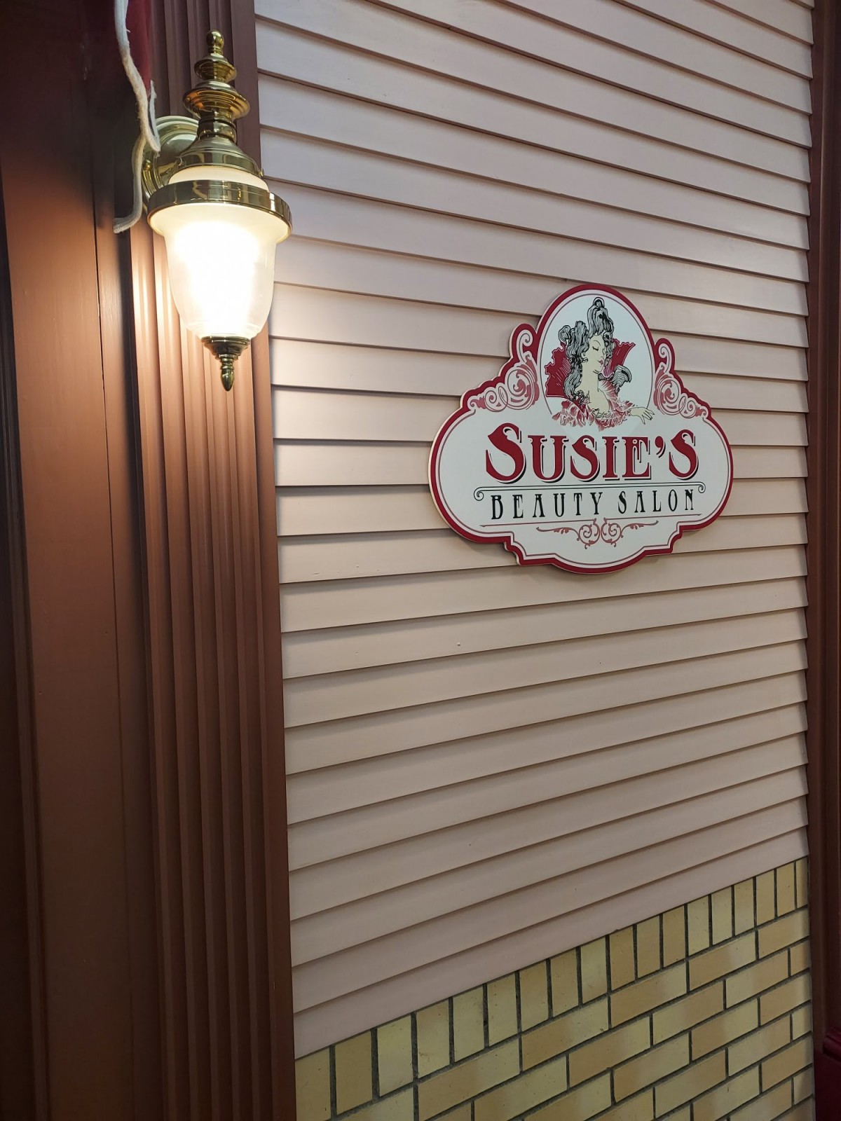 Exterior sign for Susie's shop with an outdoor lamp.