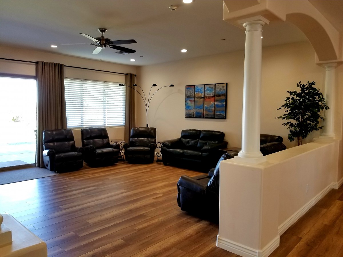 A spacious living room with leather seating, a ceiling fan, and wooden flooring.