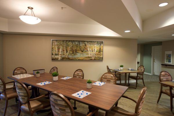 A cozy dining area with wooden tables and chairs, featuring wall art and soft lighting.