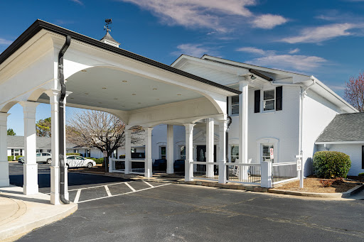 A welcoming entrance to a classic motel, featuring a charming white exterior and elegant pillars.