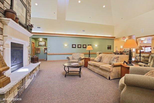 A cozy living room with sofas, a lamp, and a coffee table on a carpeted floor.