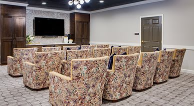 A modern theater room with patterned seating and a large TV screen.