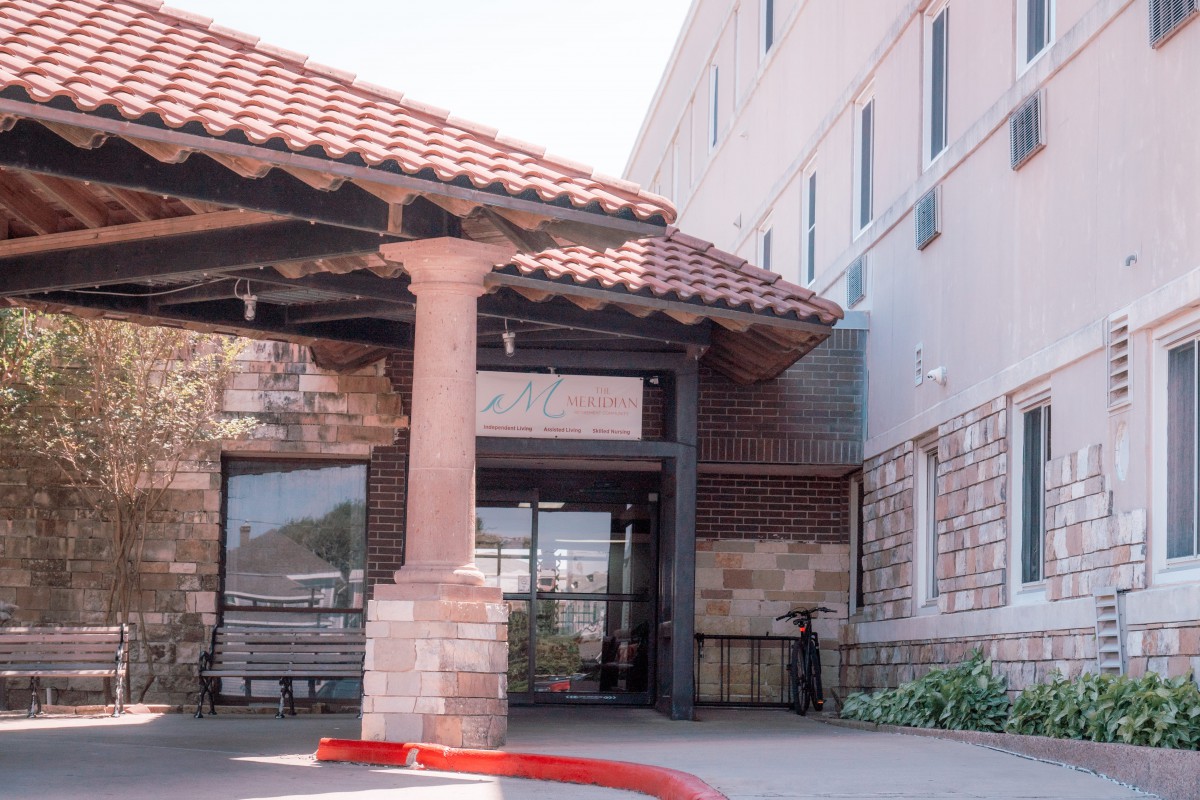 The entrance of a building with a tiled awning and brick exterior.