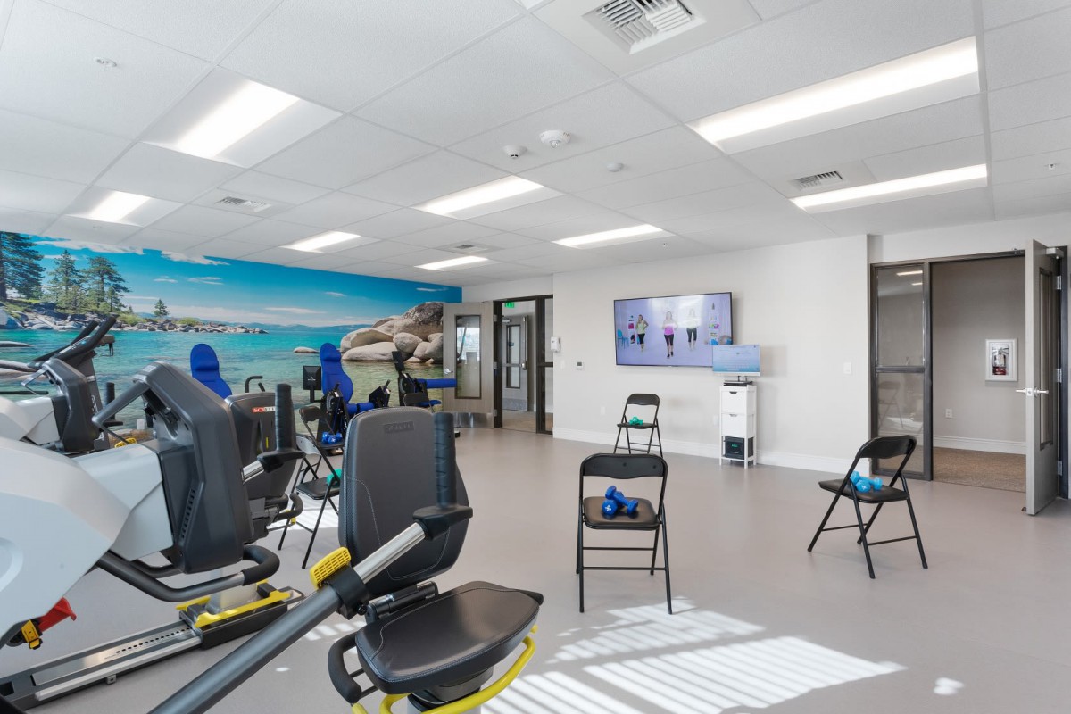 Interior of a fitness center with exercise equipment and arranged chairs.