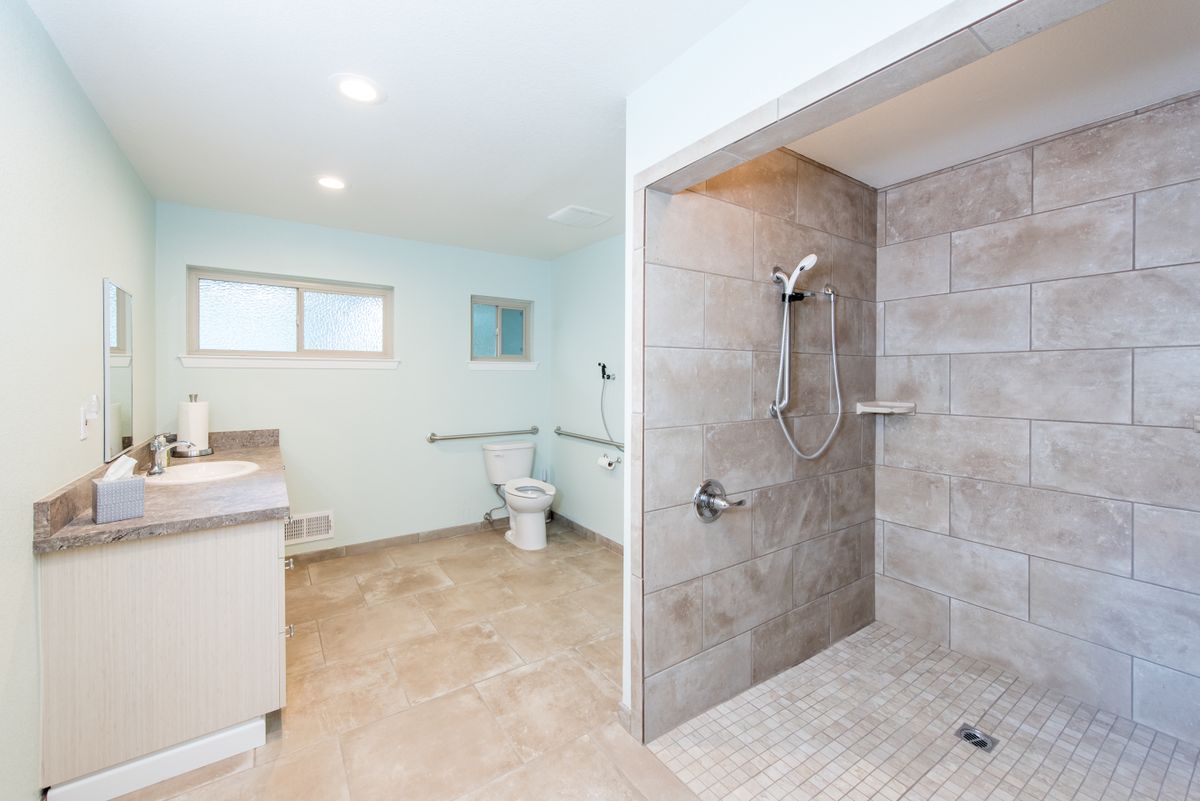 A spacious, accessible bathroom featuring a large walk-in shower and modern fixtures.