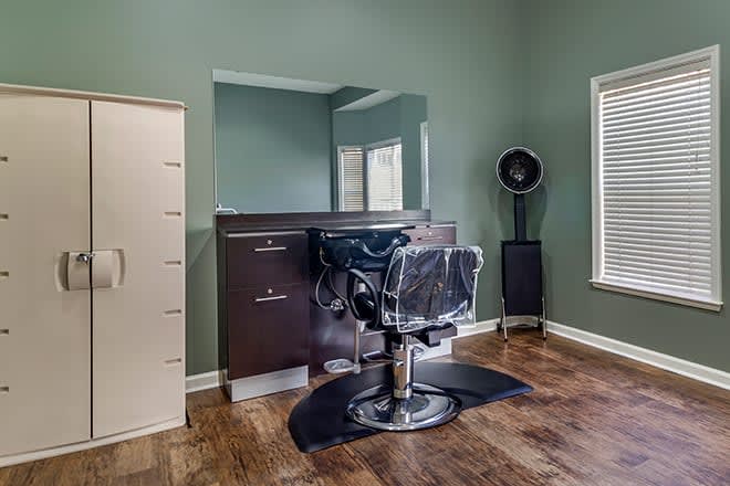 A modern barber shop interior featuring a styling chair, large mirror, and hair dryer.