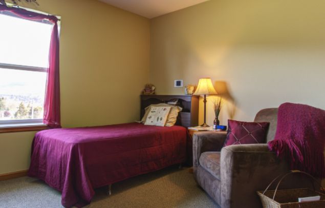 A cozy bedroom with a bed, lamp, and comfortable chair.