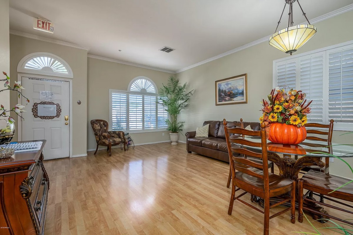 A cozy living room with a dining area, featuring hardwood floors, a sofa, chairs, and decorative elements.