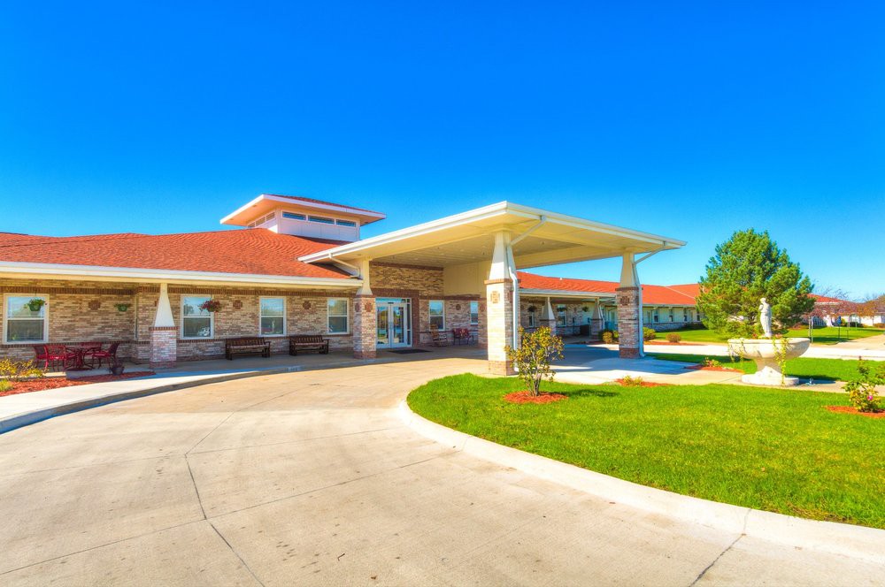 A modern building entrance with a covered walkway and landscaping on a sunny day.