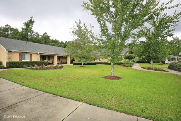 A well-maintained house with a neatly landscaped lawn and surrounding trees.