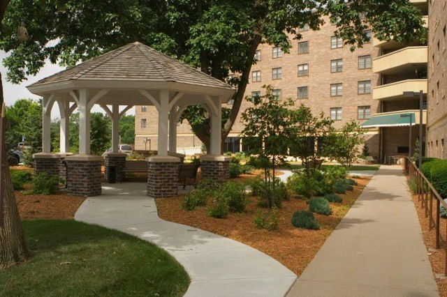 A landscaped garden with a gazebo and pathway in front of a building.