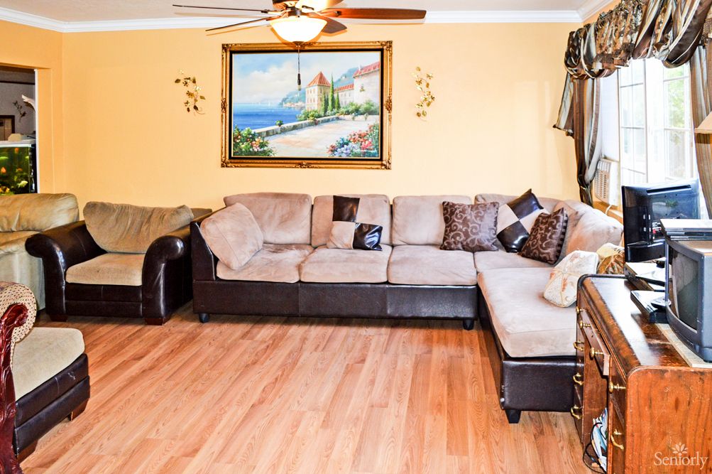 A cozy living room featuring a sectional sofa, hardwood flooring, and a scenic painting on the wall.