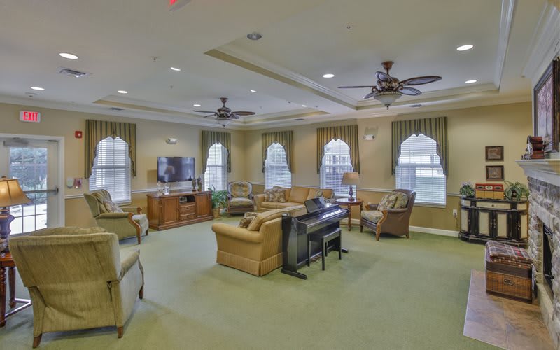 A spacious and well-furnished living room with multiple seating options and ceiling fans.