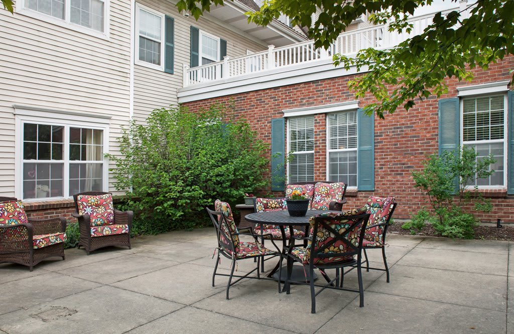 A cozy outdoor patio area with a table and chairs set against a brick wall backdrop.