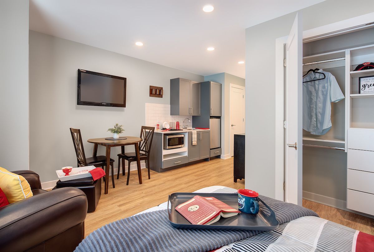 A cozy studio apartment featuring a compact kitchen and dining area with modern furnishings.