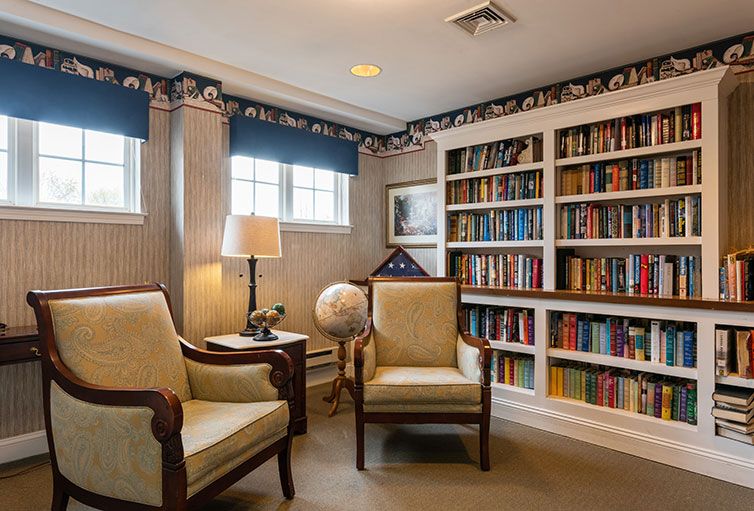 A cozy library with armchairs, a globe, and well-stocked bookshelves.