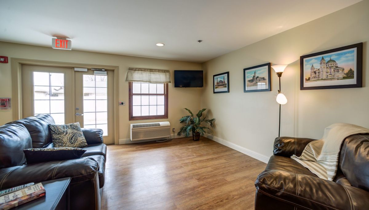 A cozy living room with wood flooring, featuring a sofa, television, and decorative artwork.