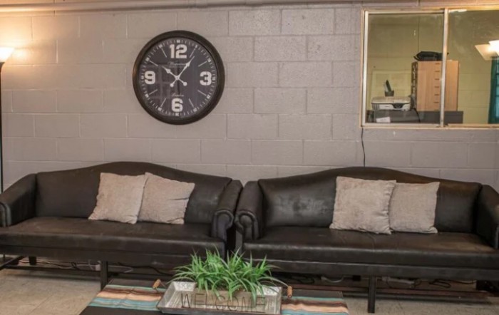 A cozy living room with two sofas, a large wall clock, and decorative elements.