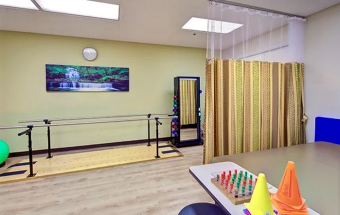 A physical therapy room equipped with parallel bars and exercise equipment.