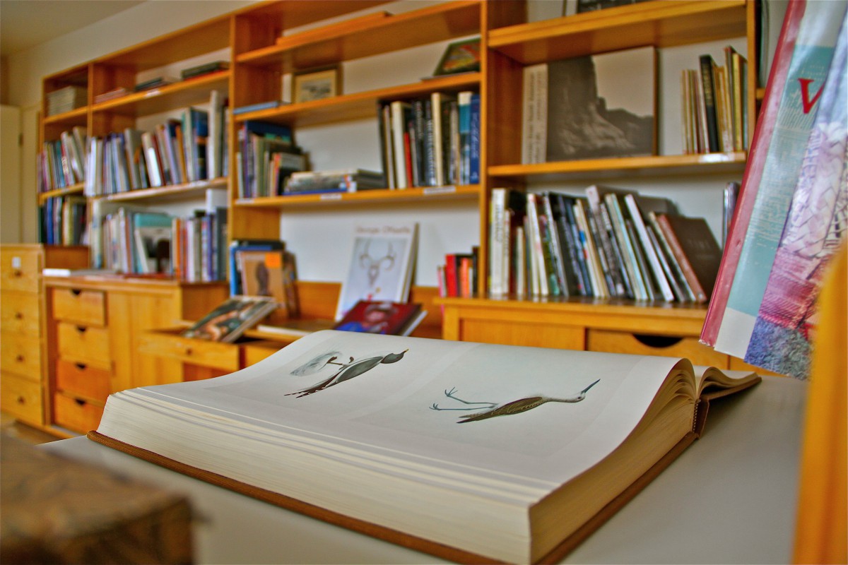 A cozy library with wooden shelves filled with books and an open book on the table.