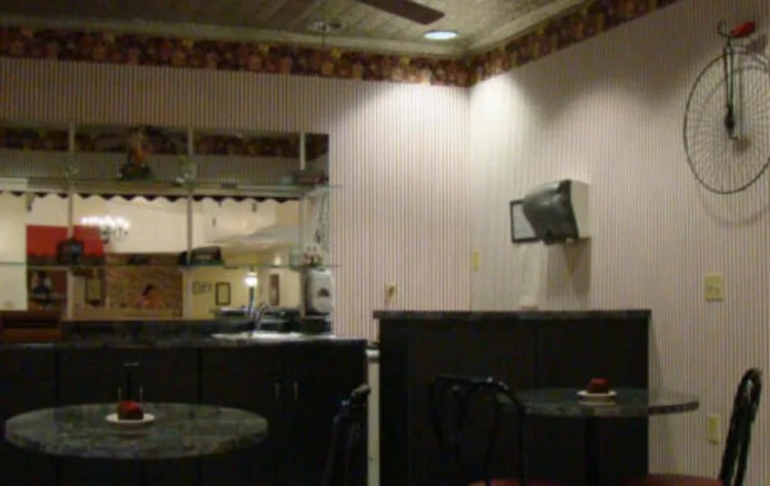 A cozy interior view of a small restaurant featuring tables, chairs, and warm lighting.