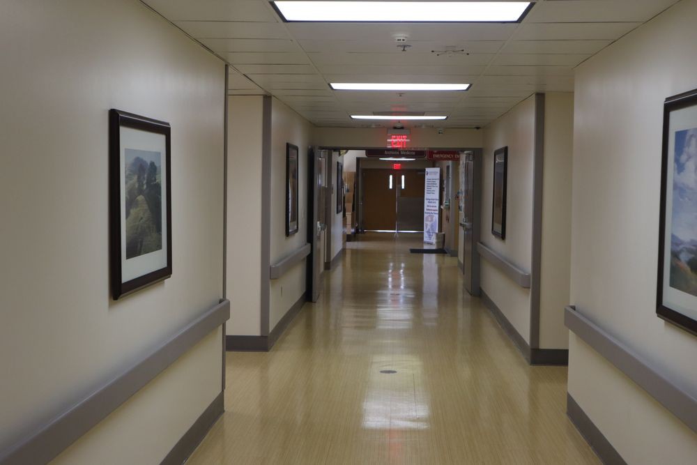 An empty hallway in a hospital setting with pictures on the walls.