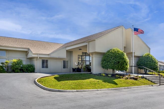 A commercial building with a landscaped entrance and a flagpole, likely a hotel.