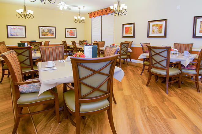 A cozy dining room with neatly arranged tables and chairs, featuring elegant decor and warm lighting.