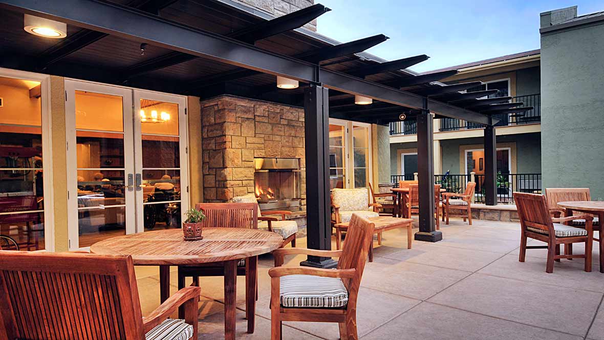 A cozy patio area with wooden furniture and a fireplace under a pergola.