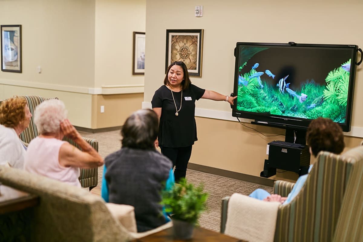 A woman giving a presentation to a small group using a television screen.