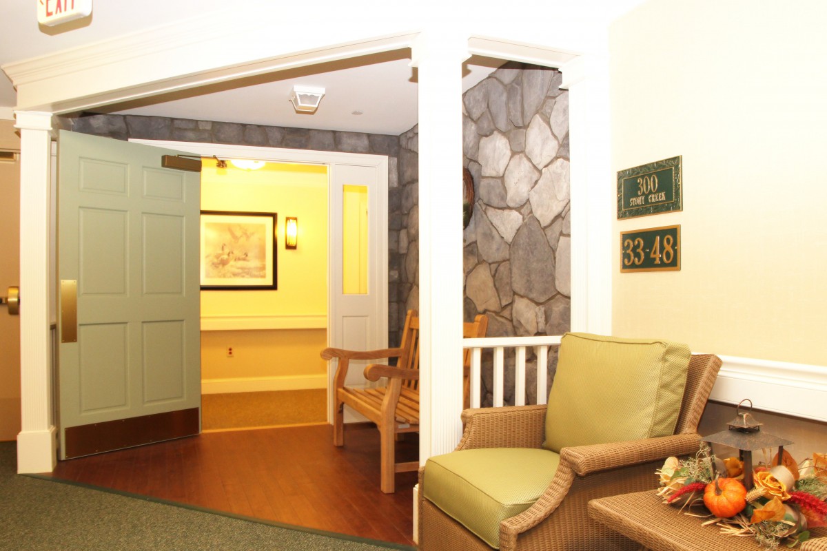 A cozy seating area with armchairs near a doorway, featuring wood flooring and stone wall decor.