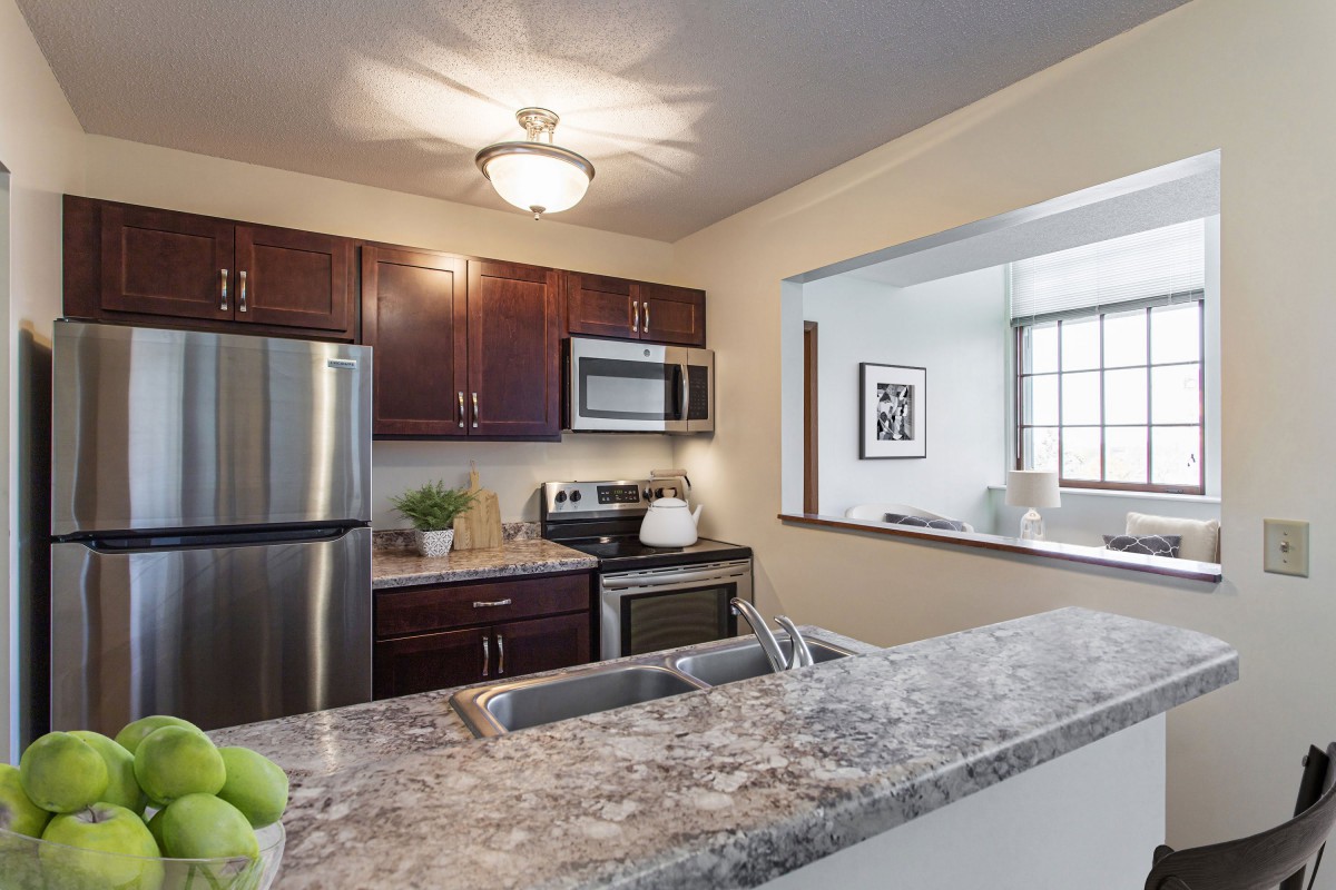 A modern kitchen with stainless steel appliances and granite countertops, featuring an open layout with dark wood cabinets.