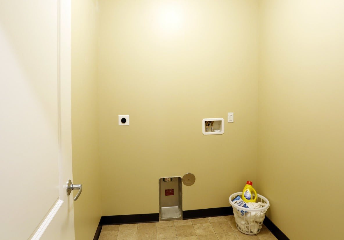 An empty laundry room with wall connections for a washing machine and dryer.