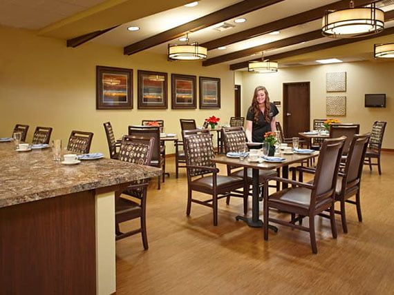 A well-lit dining area with neatly arranged tables and chairs, featuring decorative artwork on the walls.