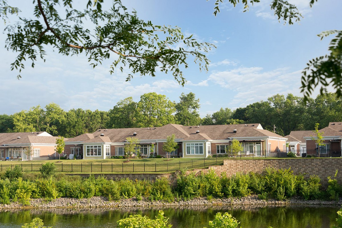 A row of houses by a tranquil waterway surrounded by lush greenery.