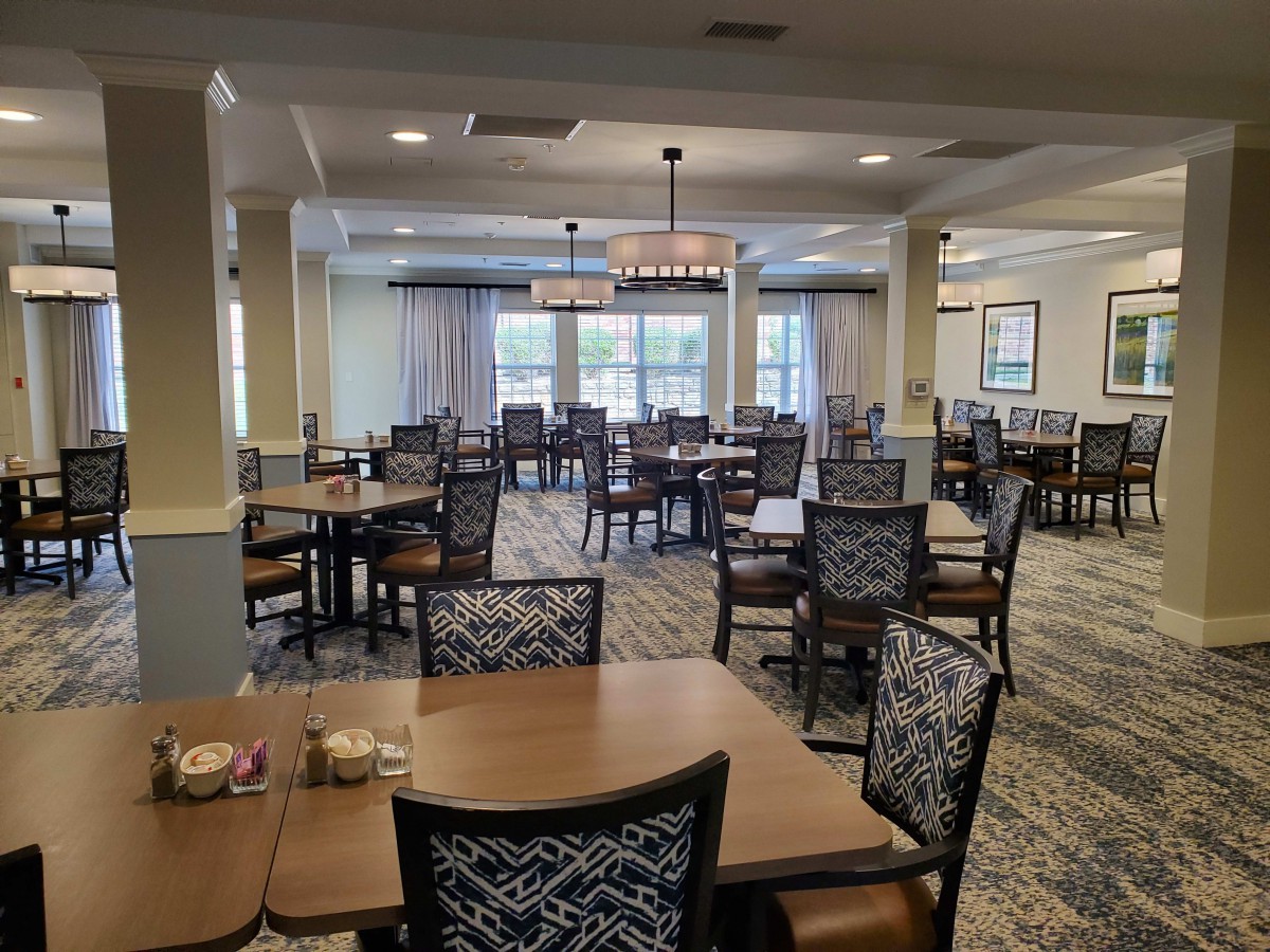 An empty dining room featuring neatly arranged tables and chairs under soft lighting.