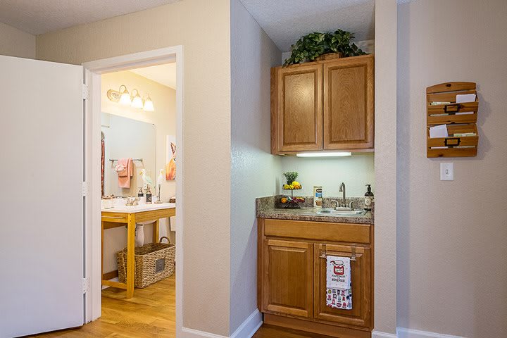 A cozy kitchenette area with wood cabinets adjacent to a bathroom.