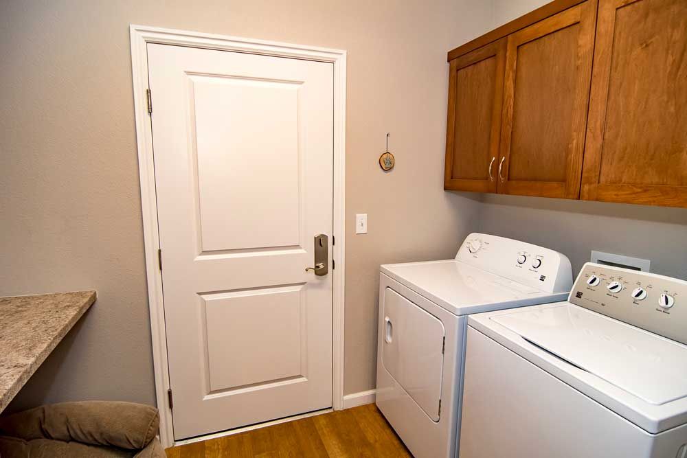 A tidy laundry room featuring a washing machine and dryer beside wooden cabinets.