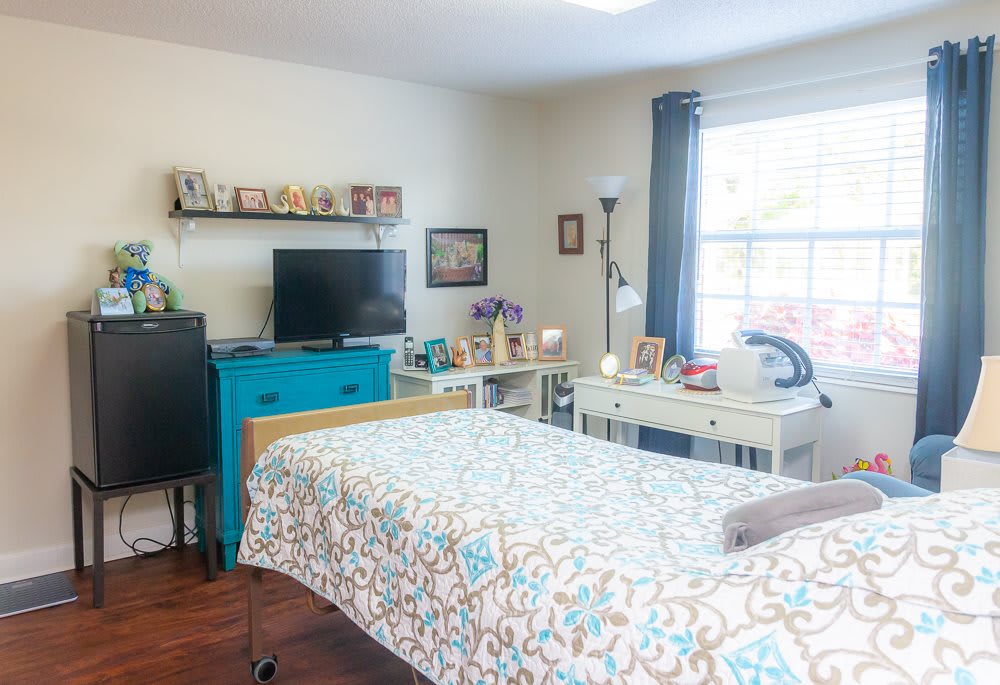 A cozy bedroom with a neatly made bed, television, and decorative touches.