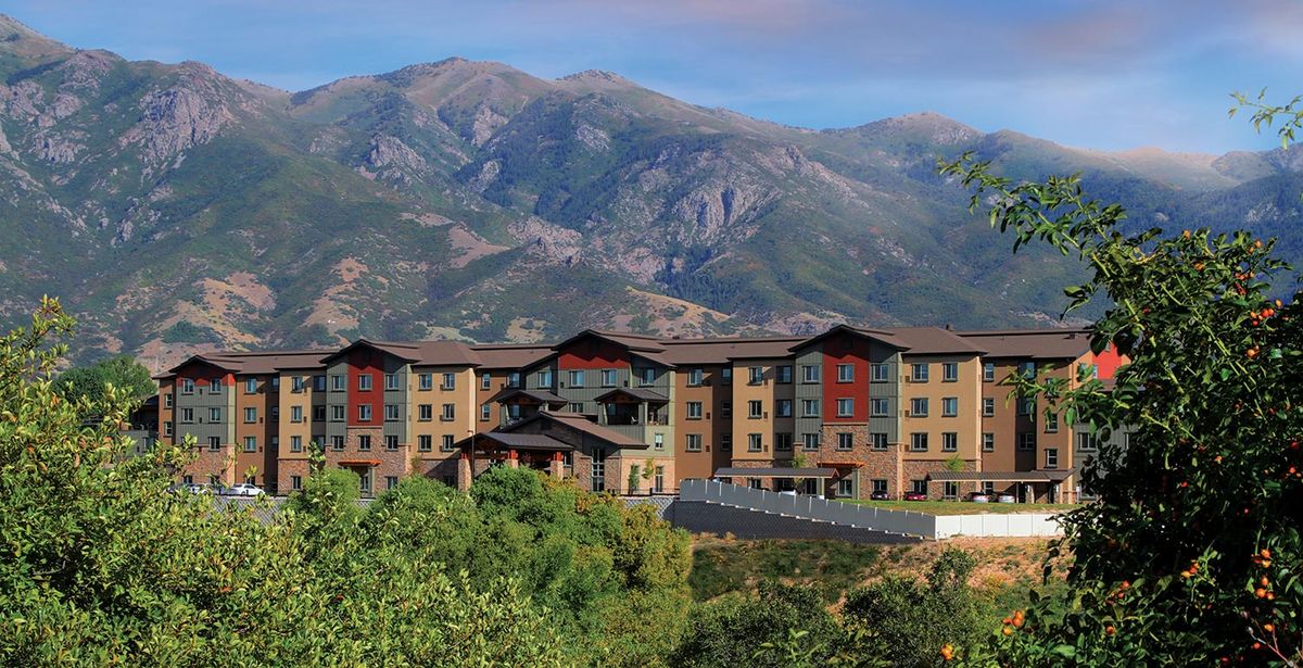 A scenic view of a building complex set against majestic mountains.