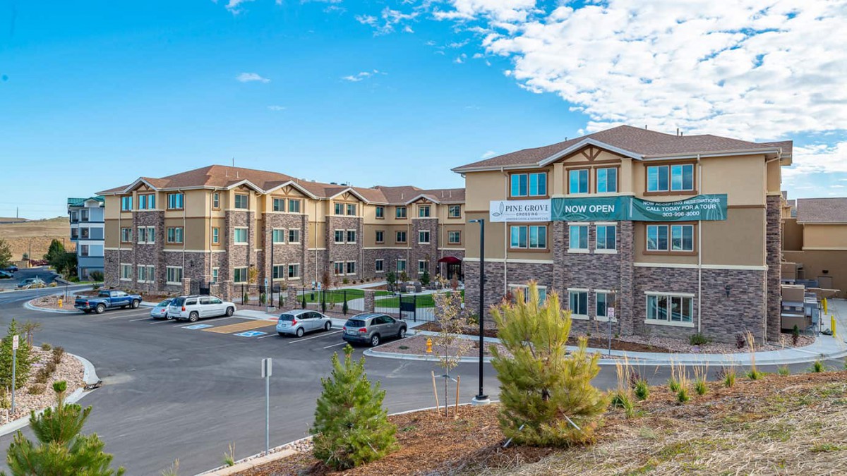 A modern residential apartment complex with a spacious parking lot and landscaped surroundings.